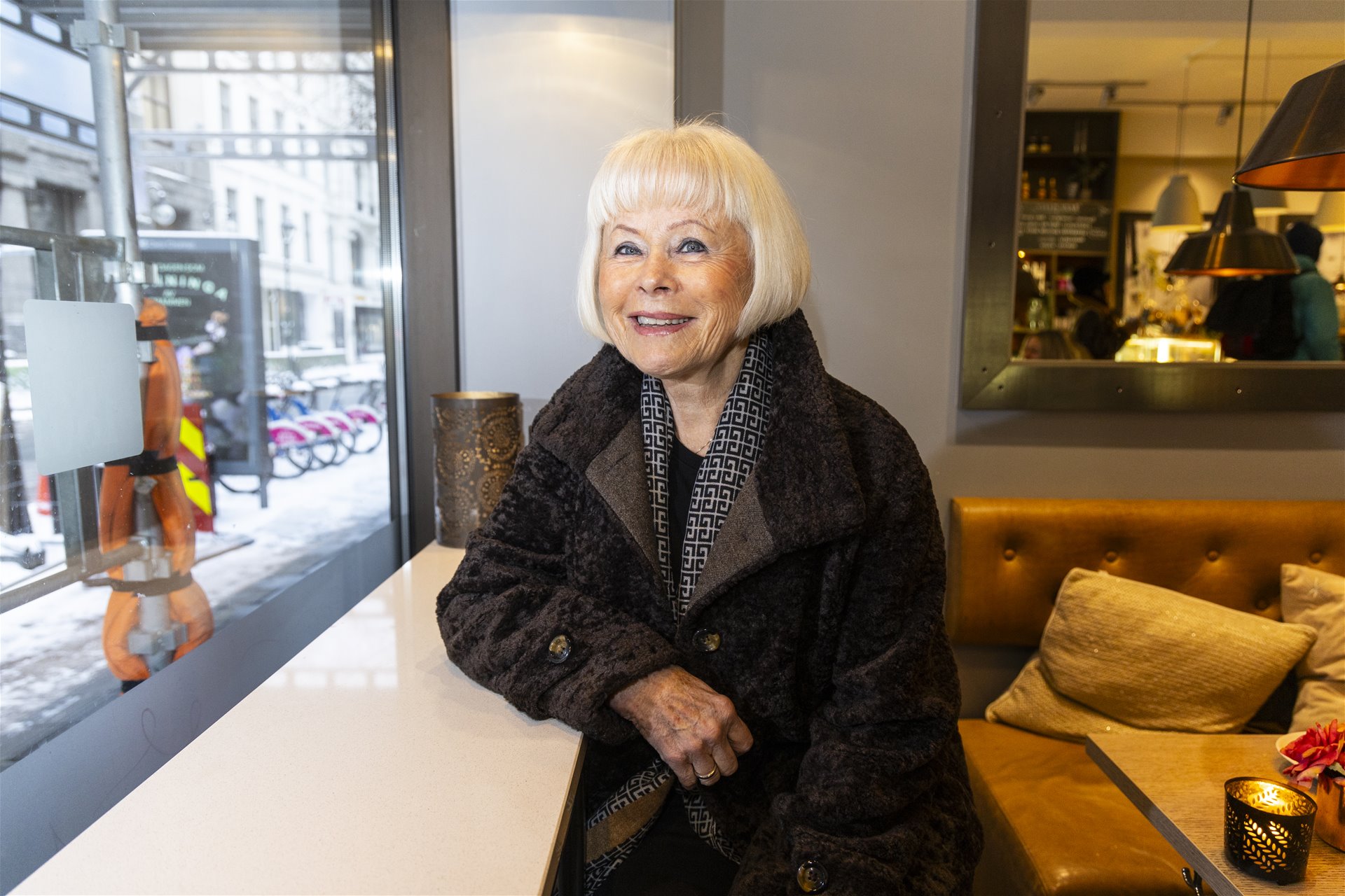 Elin Robstad sitter på cafeen ved vindusbordet. Hun smiler og ser i kameraet